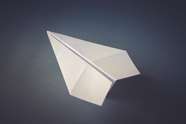 Origami d'avion en papier blanc isolé sur fond gris