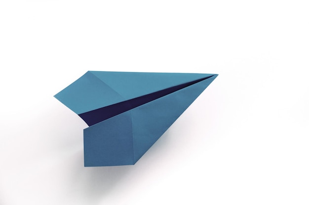 Origami avion en papier bleu isolé sur fond blanc