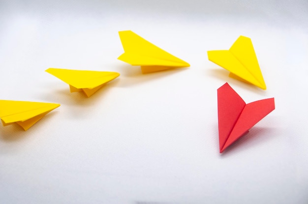 Origami d'avion en papier rouge menant des avions jaunes sur fond blanc Concept de leadership