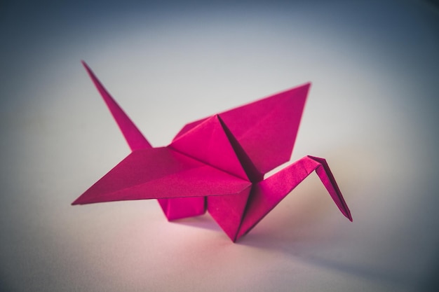 Photo origami grue papier rose isolé sur fond blanc