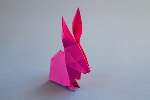 Origami de lapin en papier rose isolé sur fond gris