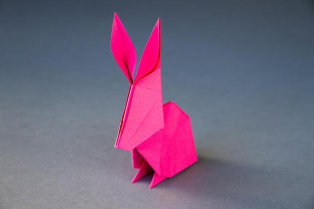Origami de lapin en papier rose isolé sur fond gris
