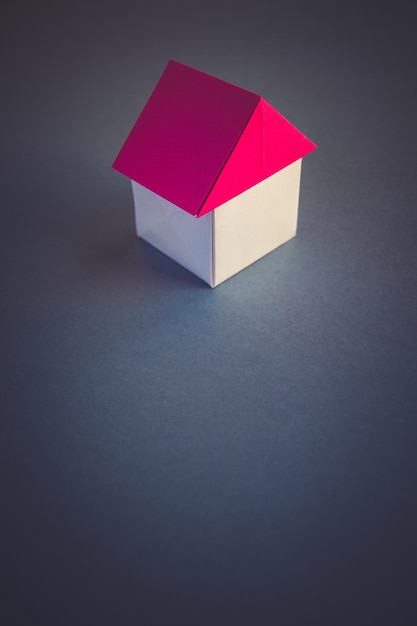 Origami de maison de papier blanc et rouge isolé sur fond gris