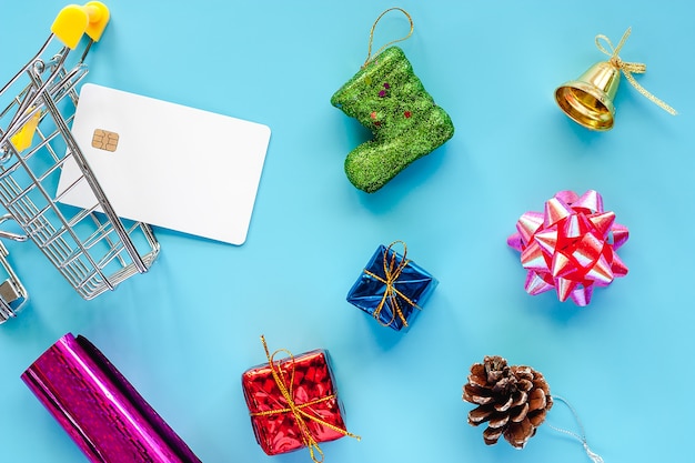 Photo ornements de noël avec carte de crédit vierge et panier sur fond bleu pour noël d