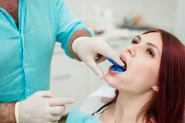 Photo l'orthodontiste montre au patient un porte-empreinte dans lequel le matériau d'empreinte en silicone sera placé pour obtenir la forme de ses dents