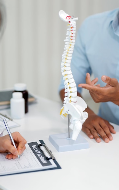 Orthopédistes tenant une tablette numérique et pointant vers le modèle Concept de l'ostéoporose douleur dorsale chiropratique lombaire et santé