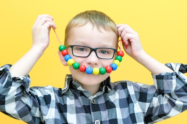 L'orthophonie le développement de la motricité fine tout-petit garçon enfile des perles sur une chaîne de perles sourire enfant heureux