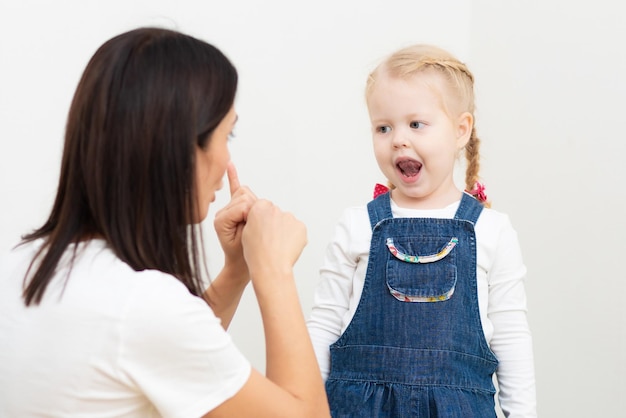 Une orthophoniste enseigne à une fille la prononciation correcte et la parole écrite