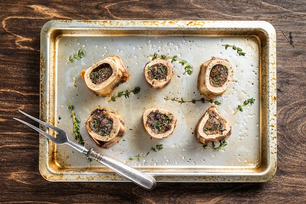 Os de boeuf à moelle rôtis dans un plat allant au four. Fond en bois. Vue de dessus.