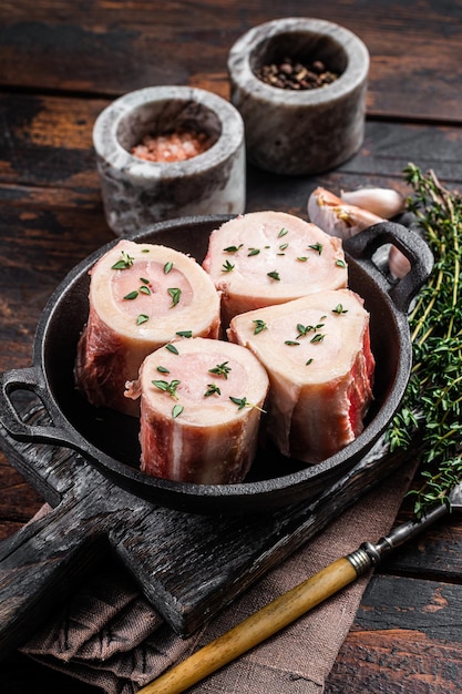 Os à moelle de boeuf cru frais dans une casserole pour la cuisson du bouillon. Fond en bois. Vue de dessus.