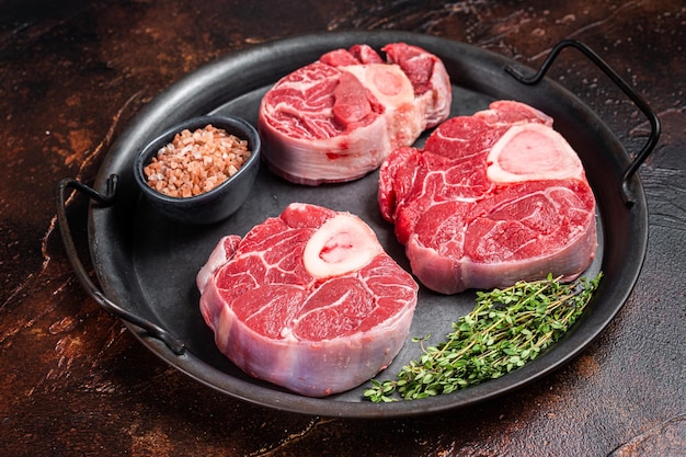 Osso buco cru Viande de bifteck de jarret de veau Ossobuco dans un plateau en acier Fond sombre Vue de dessus