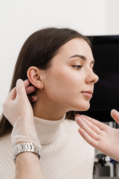 L'otoplastie est un remodelage chirurgical du pavillon ou de l'oreille externe pour corriger une irrégularité et améliorer l'apparence Un médecin chirurgien examine l'oreille d'une fille avant la chirurgie esthétique de l'otoplastie
