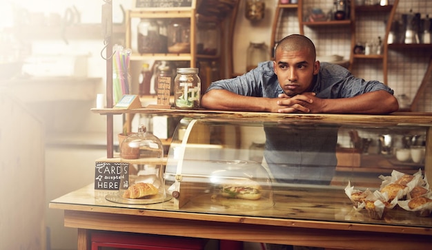 Où sont tous les clients Plan d'un jeune homme debout derrière le comptoir de son magasin et l'air découragé