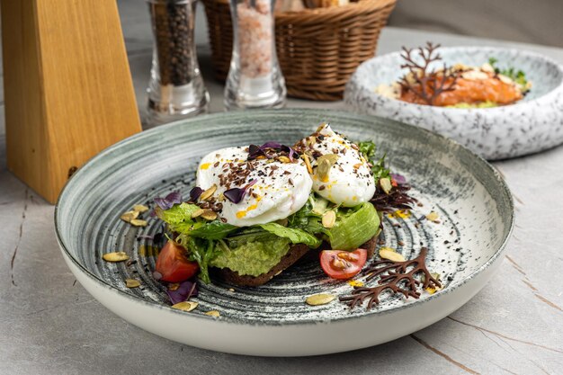 Oue poché avec des tomates à la cerise à l'avocat et de la salade de ragoule