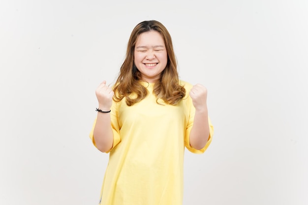 Oui geste de célébration de la belle femme asiatique portant un T-shirt jaune isolé sur fond blanc