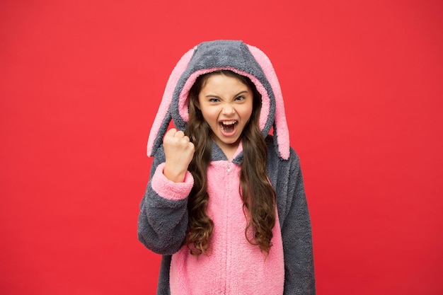 Oui je peux. Concept de mode de vie. Repose toi et relaxe toi. Enfant de lapin mignon sur fond rouge. Rôle de personnage de bébé animal. Superbe fille en costume de lapin. Enfant en lapin kigurumi. Fille heureuse en pyjama lapin.