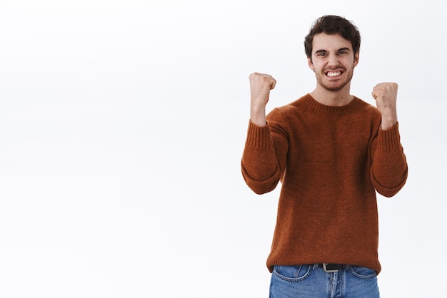 Oui, nous l'avons fait Triomphant jeune heureux homme chanceux gagner le prix pompe de poing célébrant joyeusement la bonne nouvelle victoire et concept de succès souriant satisfait faire la danse championne sur fond blanc