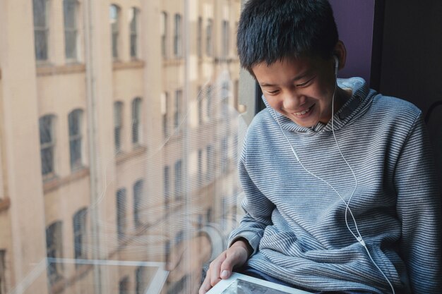 Oung mixte préadolescent asiatique utilisant une tablette numérique à la maison