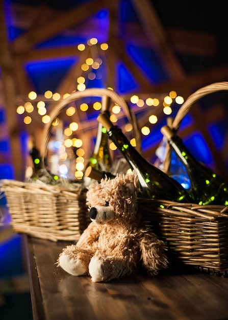 Ours en peluche bouteille de champagne avec panier de Noël guirlandes d'or sur fond de bois brun foncé célébration du nouvel an conceptxA