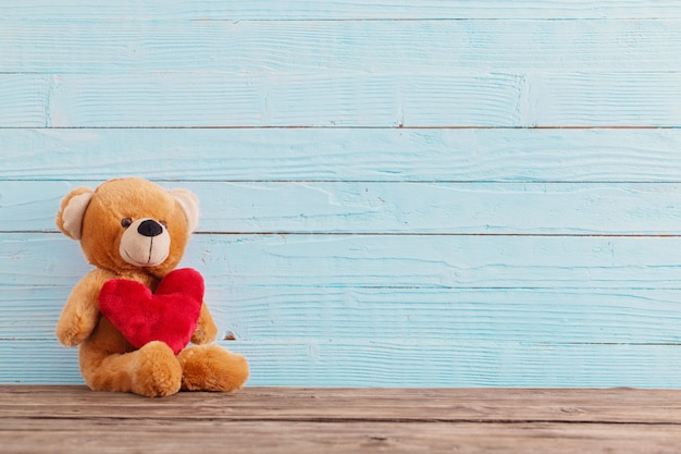 Photo ours en peluche avec coeur rouge sur fond de bois ancien. concept de la saint-valentin