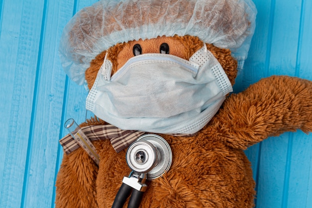 Photo ours en peluche dans un masque médical protecteur et stéthoscope