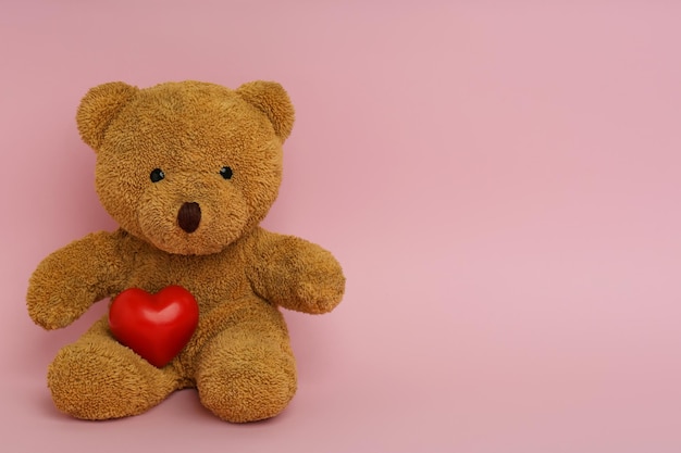 Ours en peluche mignon avec coeur rouge sur fond rose espace pour texte célébration de la Saint-Valentin