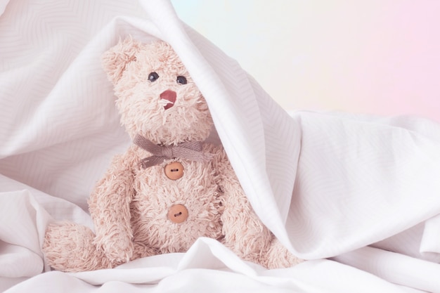 Ours en peluche mignon jouer à cache-cache avec le tissu, concept de sentiment heureux.