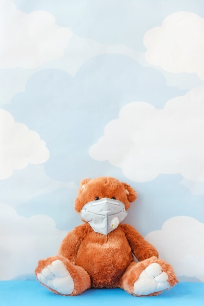 Ours en peluche portant un masque contre la grippe se trouve sur fond de ciel bleu. Concept malade, ou pollution de l'environnement, pollution par les gaz.