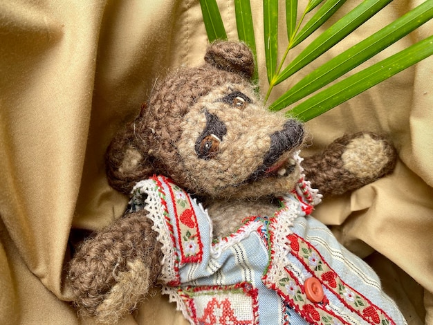 Photo un ours en peluche avec une robe bleue avec une bordure rouge et un cœur rouge dessus.