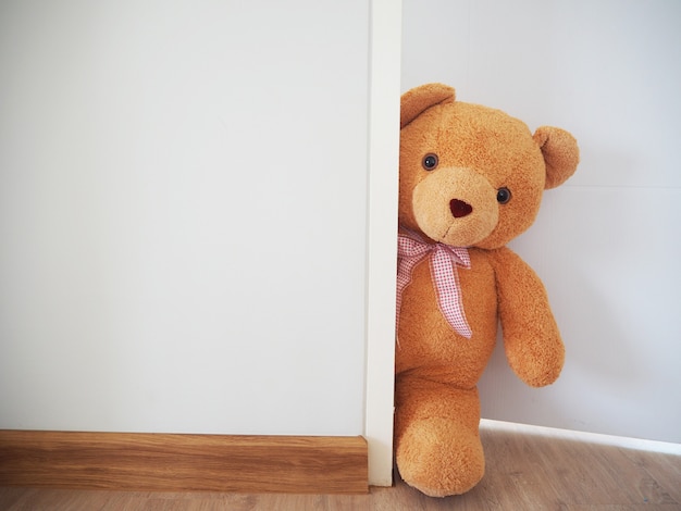 L'ours en peluche se tenait secrètement derrière le mur.