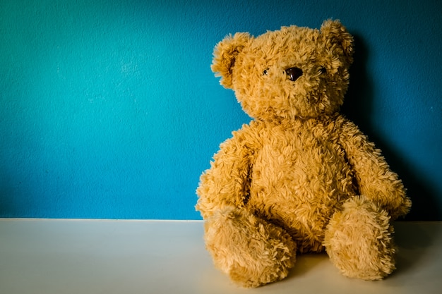 Photo ours en peluche sur une table blanche avec un fond bleu.