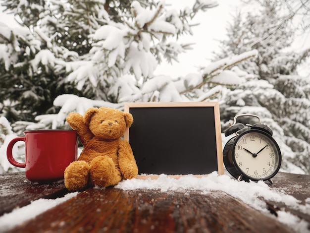 Ours en peluche et tableau noir avec réveil sur table en bois en blizzard