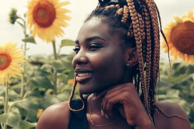 Outdoor portrait of beautiful happy mixed race African American girl adolescent femme jeune femme dans un champ de fleurs jaunes au coucher du soleil soleil du soir doré
