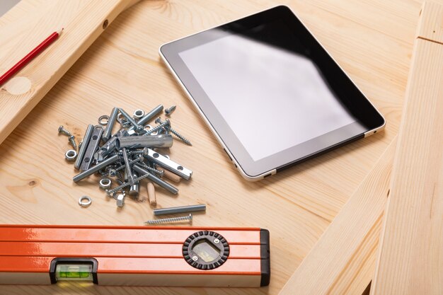 Outil de construction et une tablette numérique se trouvent sur une table en bois clair