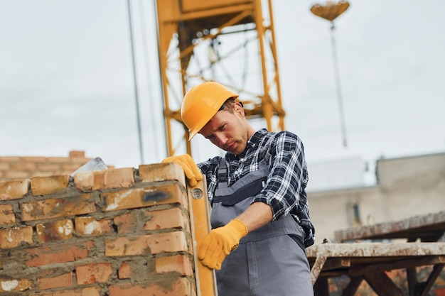 Avec outil de mesure de niveau Travailleur de la construction en uniforme et équipement de sécurité ont un travail sur la construction