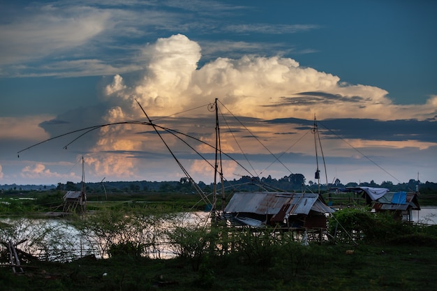 Outil de pêche traditionnel ou piège à poisson en bambou sur la lumière du coucher du soleil, silhouette du paysage.