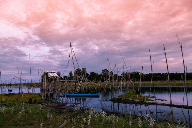 Outil de pêche traditionnel ou piège à poisson en bambou sur la silhouette du paysage de lumière au coucher du soleil