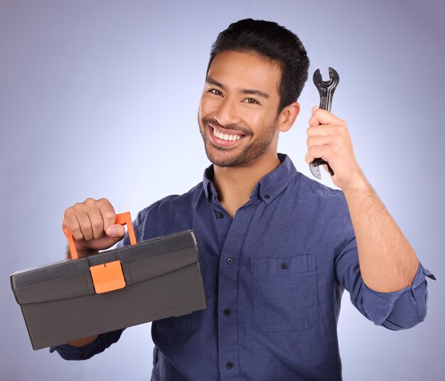 Outil de portrait et homme asiatique avec boîte sourire et entretien avec gars sur fond de studio bleu Visage employé masculin et bricoleur avec équipement de bonheur et entrepreneur avec service et heureux