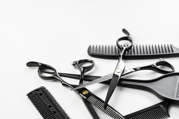 Outils de coiffure noirs et brosses à cheveux diverses sur fond blanc