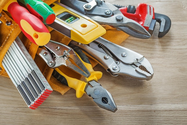 Outils de construction dans la ceinture à outils sur planche de bois