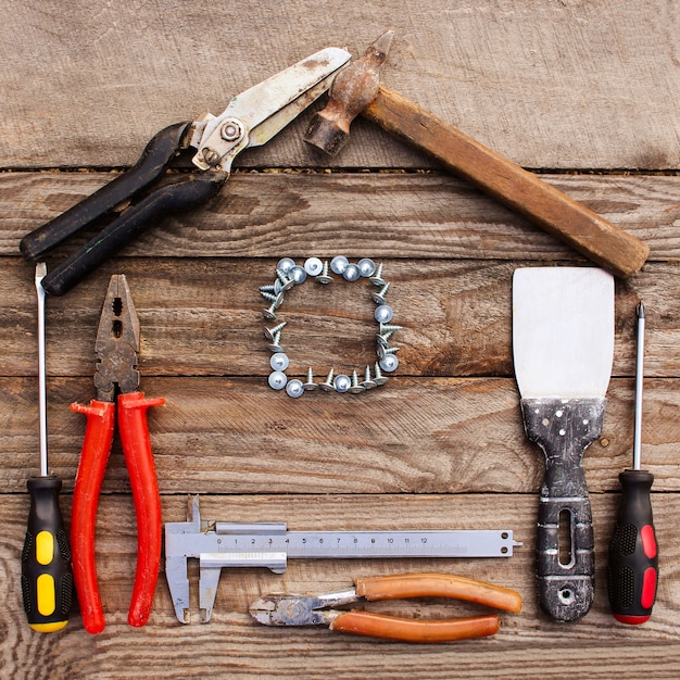 Outils de construction sous forme de maison sur fond en bois.