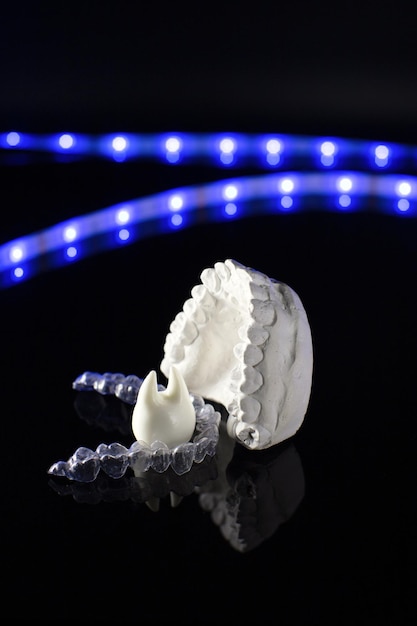 Outils dentaires et modèle de dents sur fond néon Concept de soins dentaires Bretelles invisibles