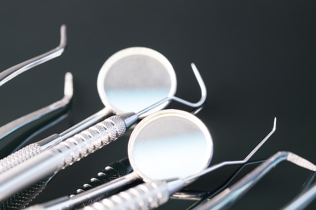 Outils dentaires utilisés par le dentiste au bureau ou à la clinique. Sur le fond noir
