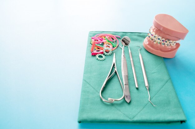 Outils de dentiste et modèle orthodontique sur fond bleu.