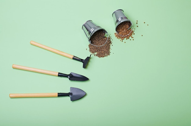 Outils de jardin, graines sur fond vert clair avec espace de copie.