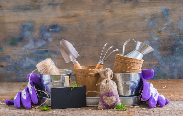 Outils de jardinage, pots et ustensiles sur fond de bois rustique, avec un tableau noir