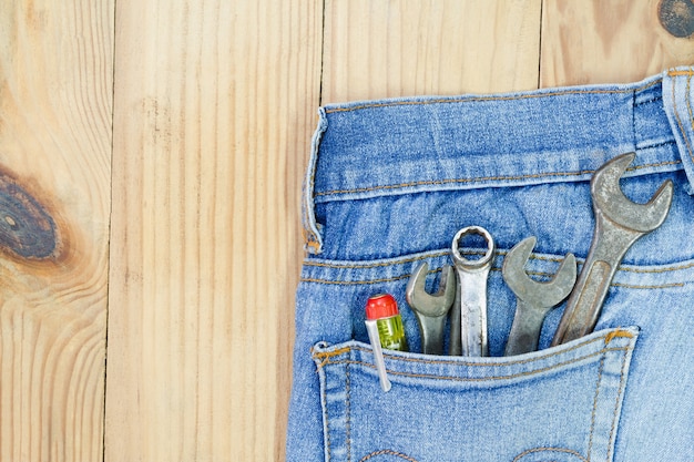 Outils à main dans la poche de jeans sur la table en bois