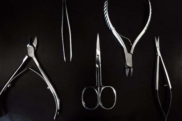 Outils de manucure et de pédicure sur fond noir lime à ongles pince à épiler pinces à poussoir glands outils médicaux vue de dessus