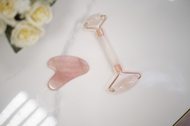 Photo outils de massage du visage pink gua sha rouleau de jade de quartz rose sur fond gris traitement anti-âge de levage et de tonification à la maison vue de dessus espace de copie