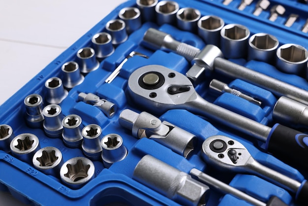 Outils de mécanicien automobile dans une boîte en plastique sur une table en bois blanche en gros plan